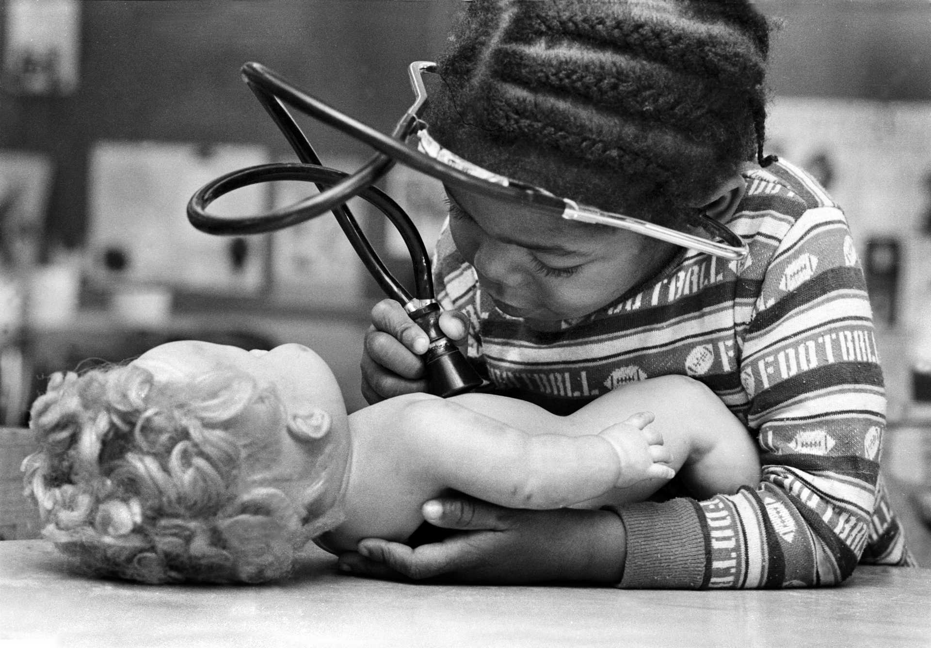 An aspiring doctor examines her doll. 1981