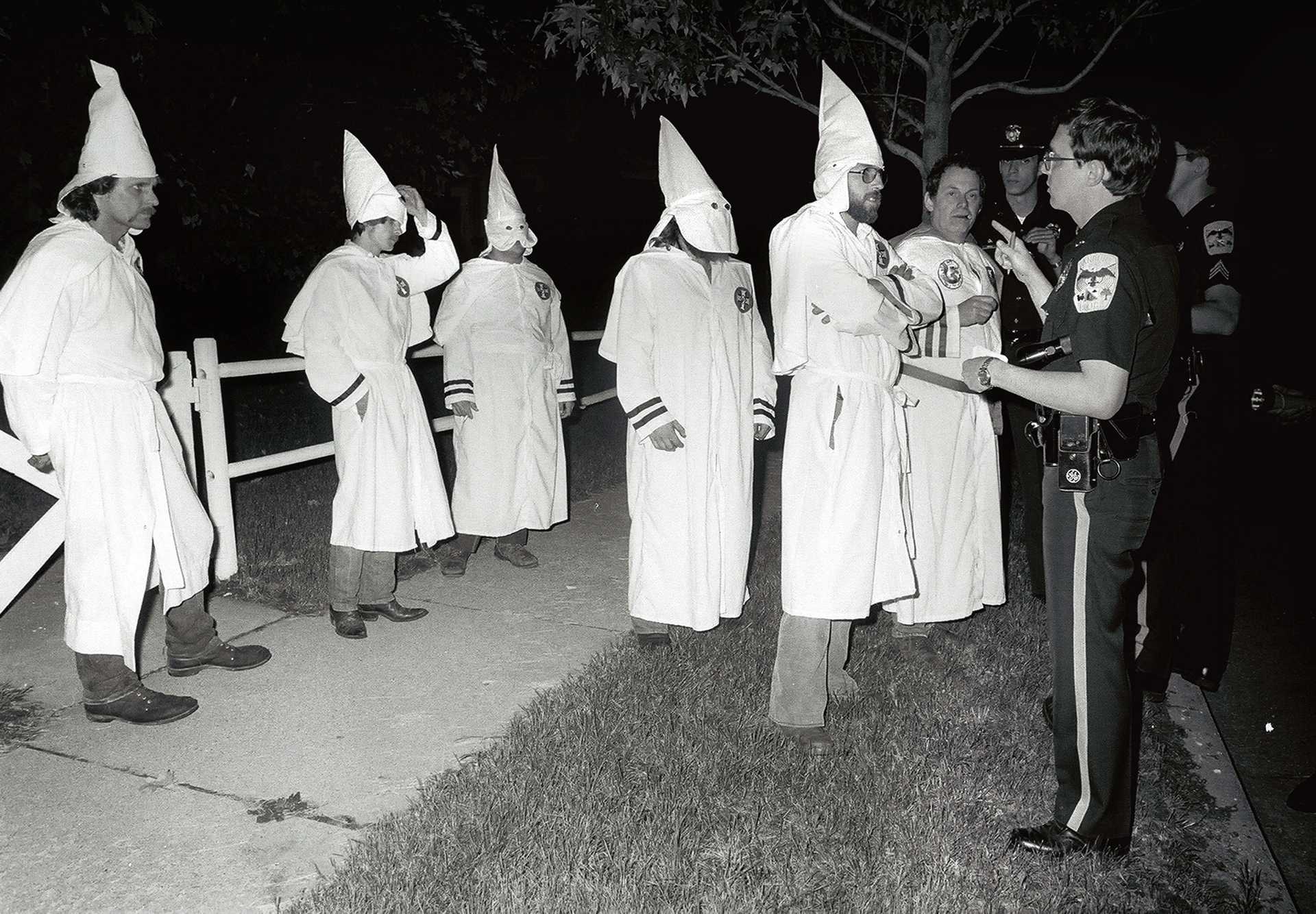 Ku Klux Klansmen are questioned by Danbury police for riding up and down Main Street shouting racial obscenities and advertising an upcoming rally in the city. 1982