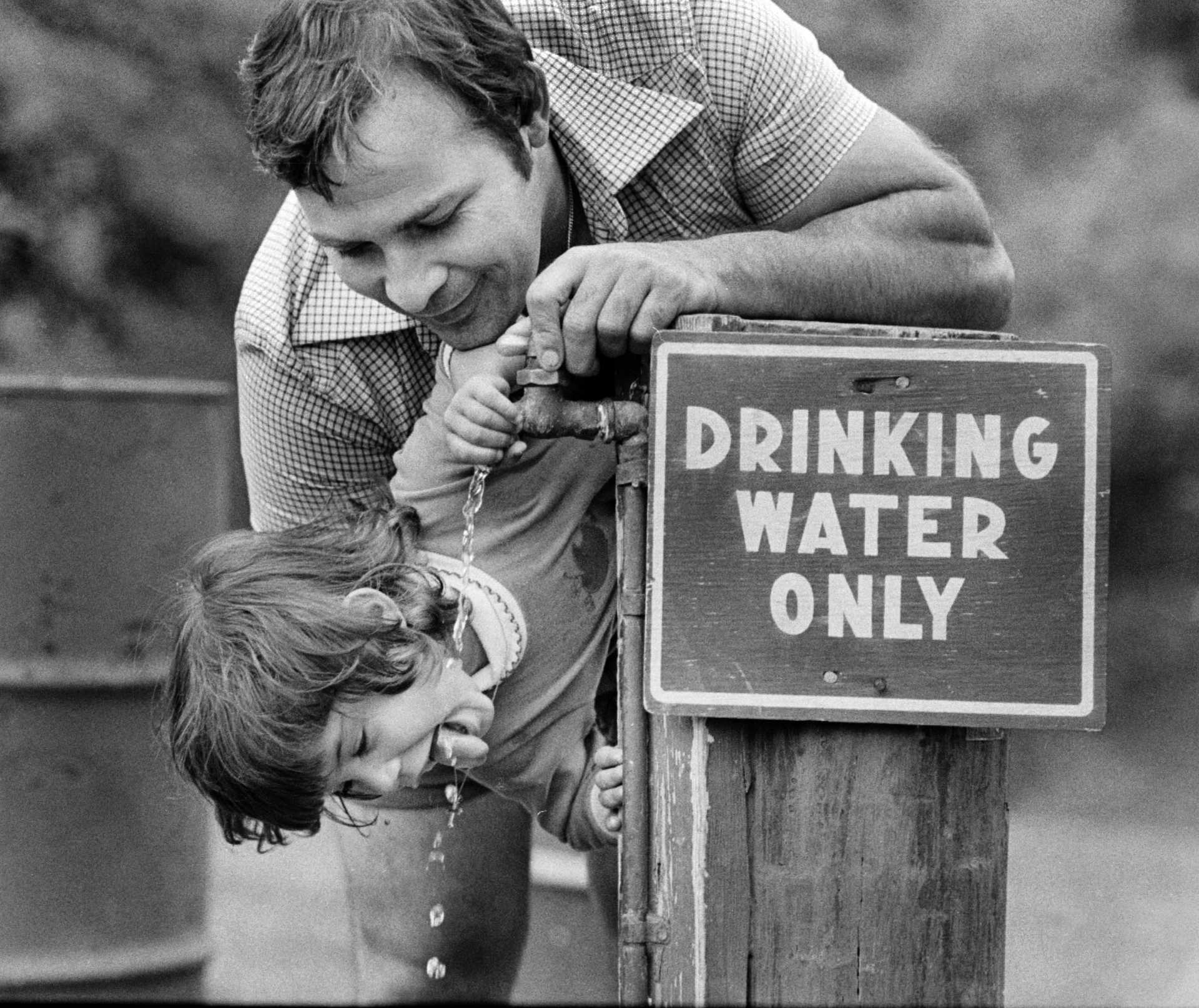 A thirsty kid with his obliging father. 1980