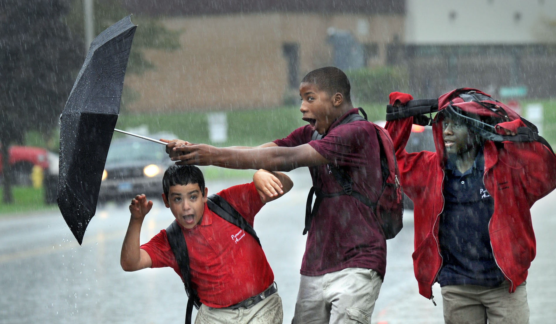 Young boys walk home from school in the pouring rain.  