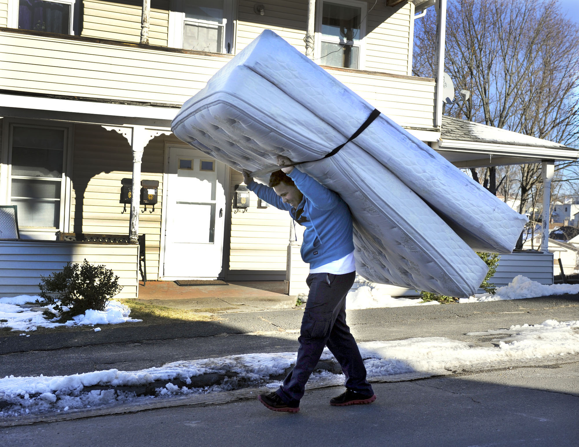 Ramon Tavera, 21, carries his mattress and boxspring to his home on Comstock Street in Danbury. 