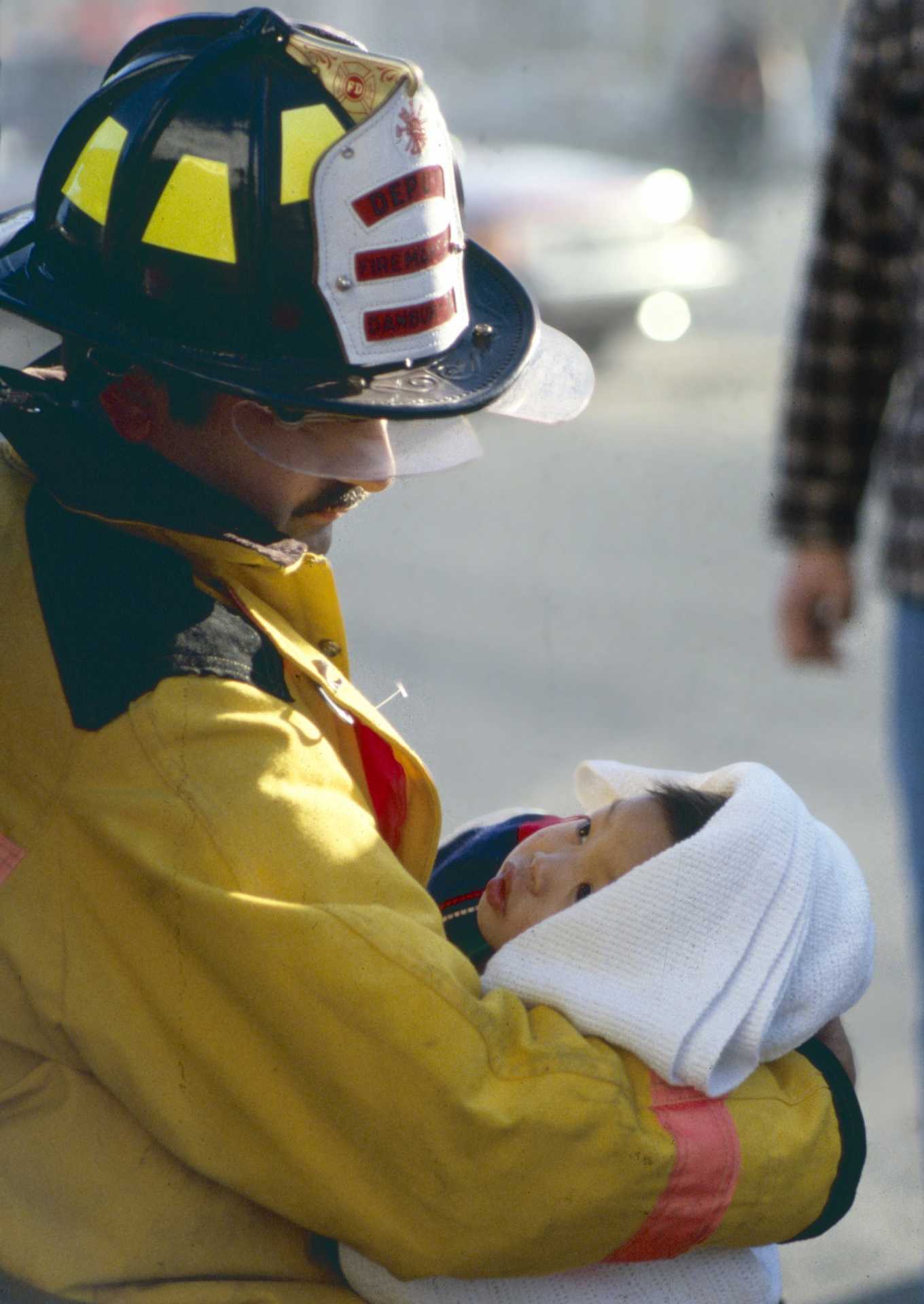Deputy Danbury Fire Marshal Barry Rickert comforts a small child whose family apartment was destroyed by fire. 