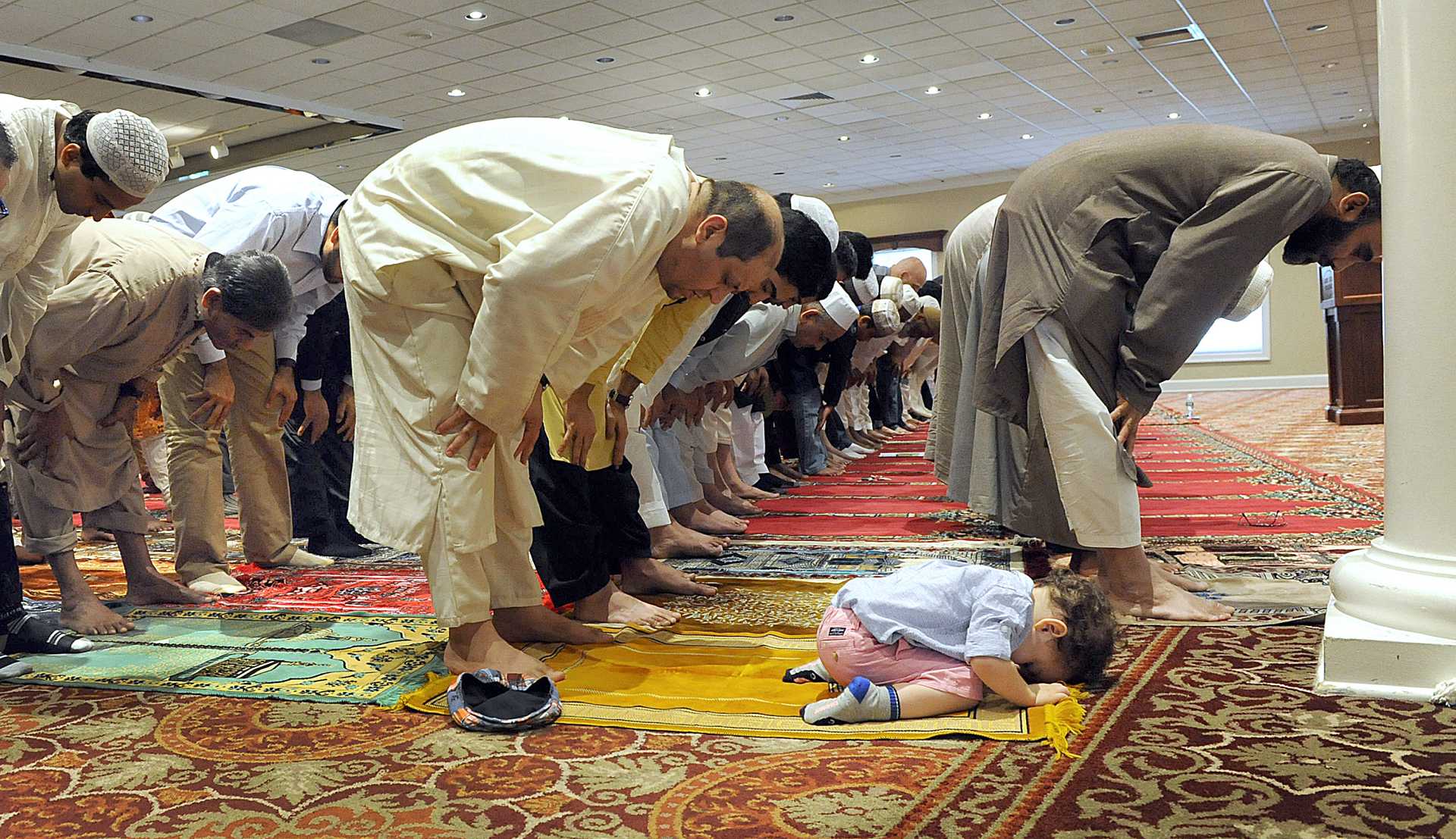 Father and son bow in reverence during an Eid prayer service marking the end of Ramadan.  <br>
