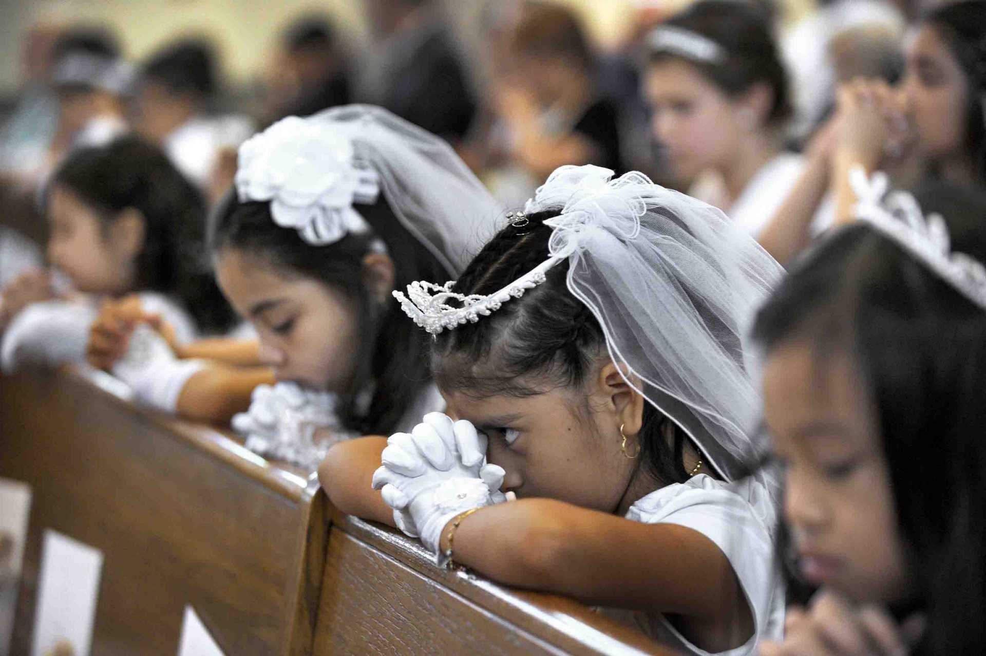 A young girl peeks up during a time of prayer at her  First Holy Communion mass.